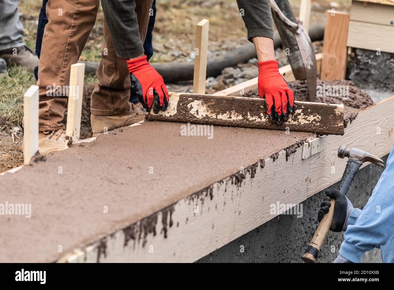 Construction Worker Leveling Wet Cement Into Wood Framing Stock Photo