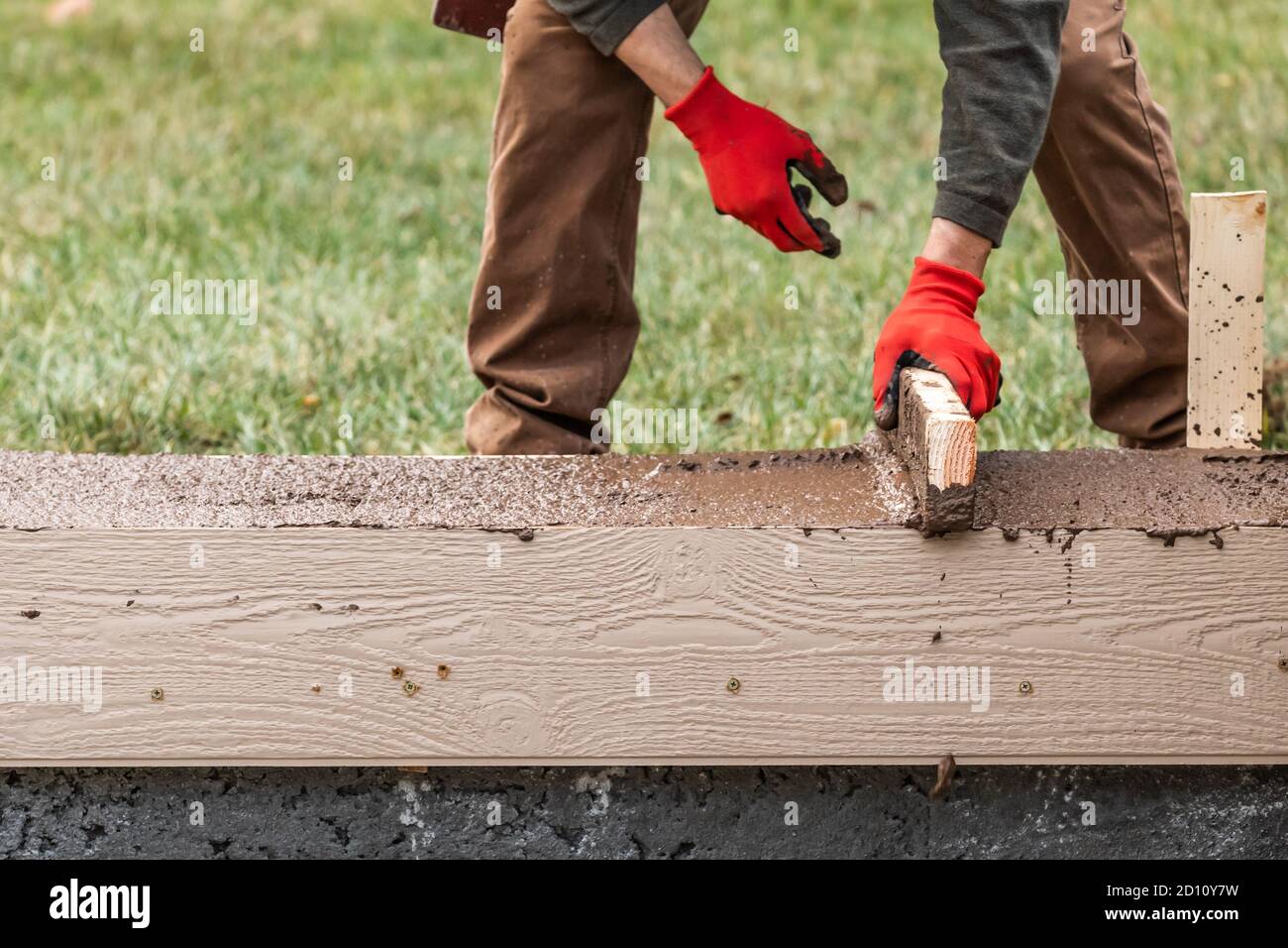 Construction Worker Leveling Wet Cement Into Wood Framing Stock Photo