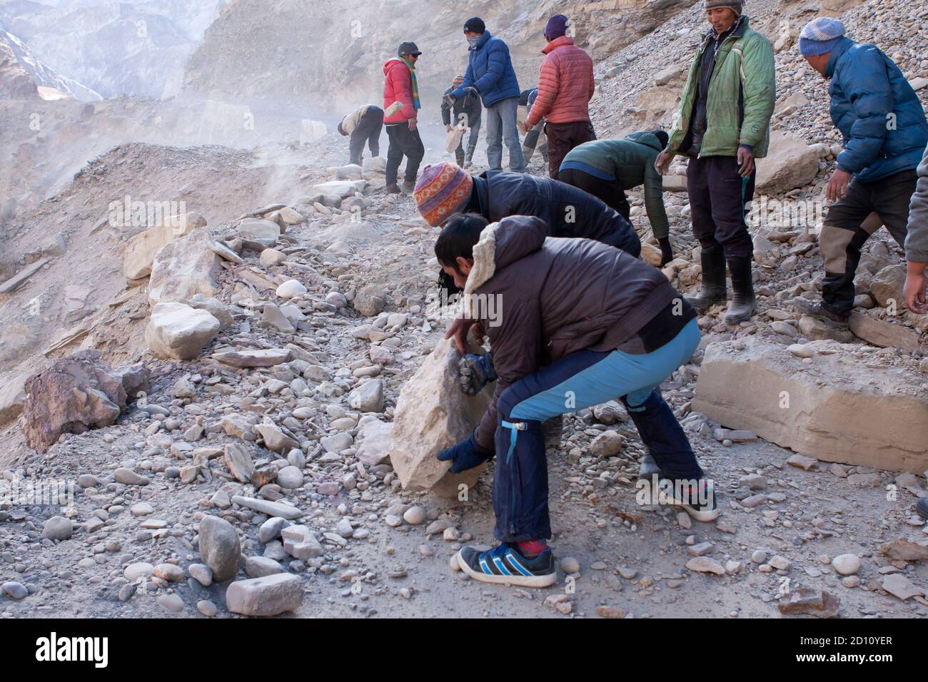 Men moving boulders, clearing road blocked due to land slide in a remote Himalayan high altitude road in Ladakh Stock Photo