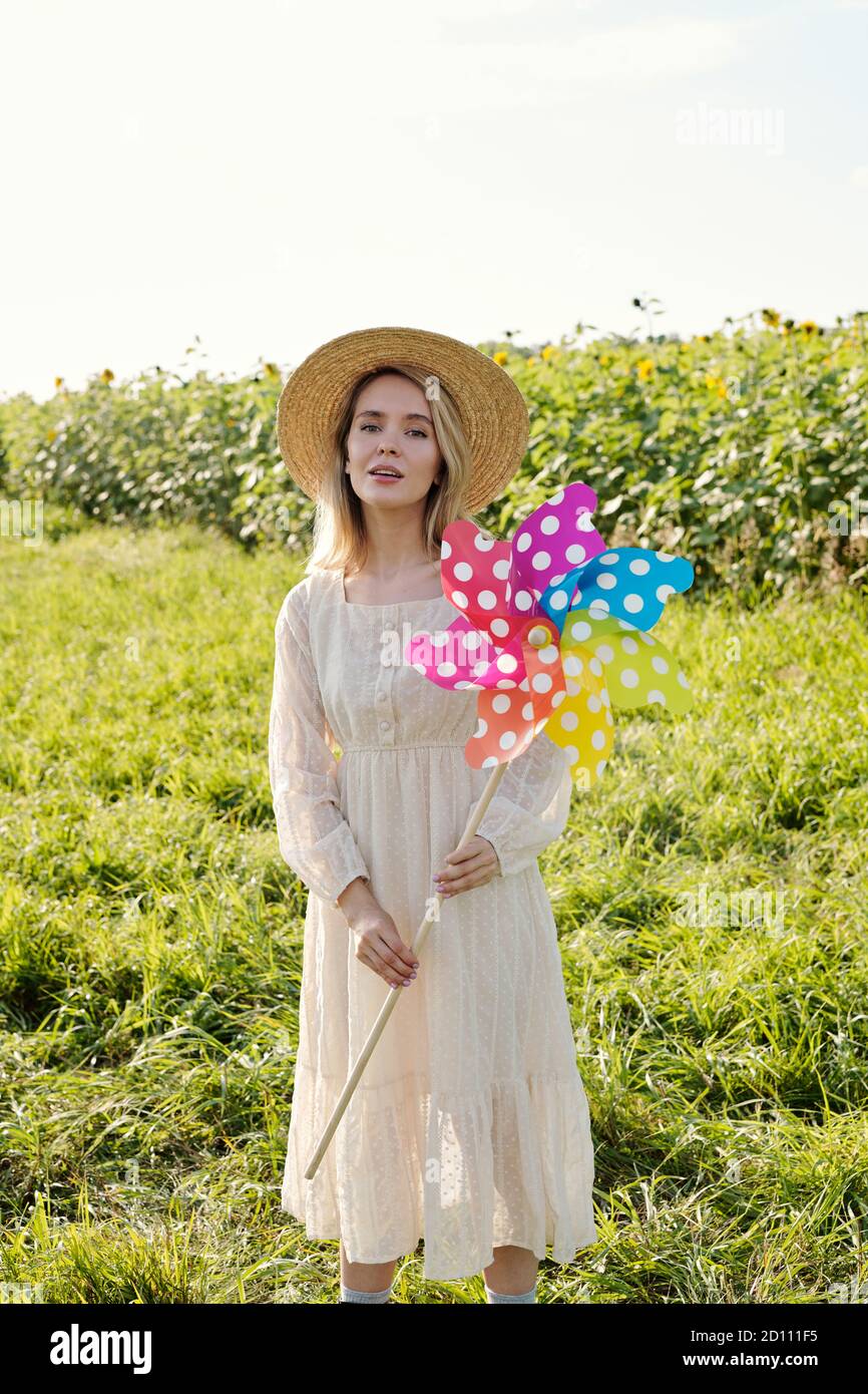 Gorgeous young blond woman in hat and dress holding large polkadot whirligig Stock Photo