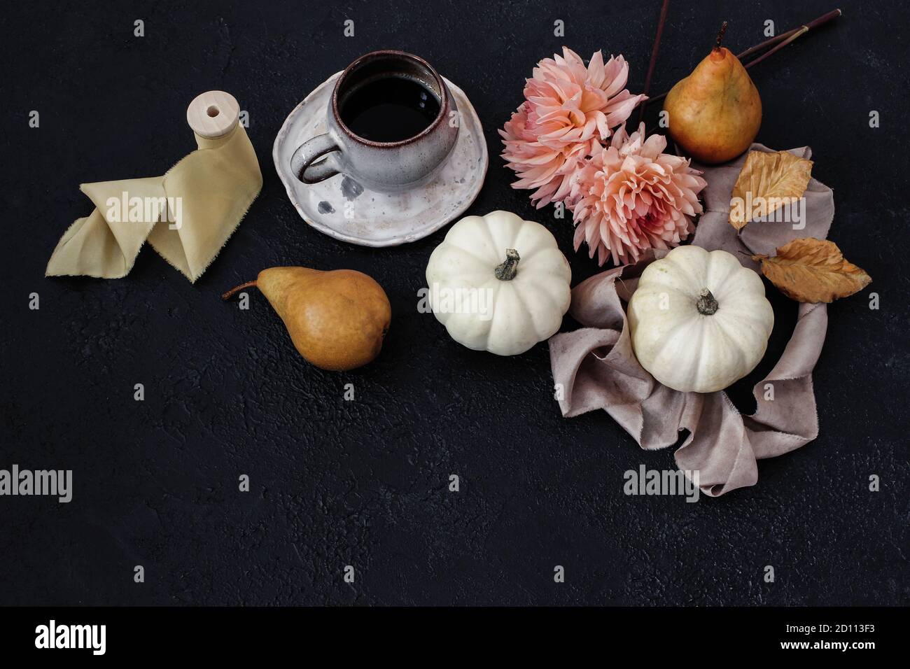 Autumn still life composition. Cup of coffee, pear fruit and white pumpkins with pink dahlia flowers on black table background. Moody fall Stock Photo