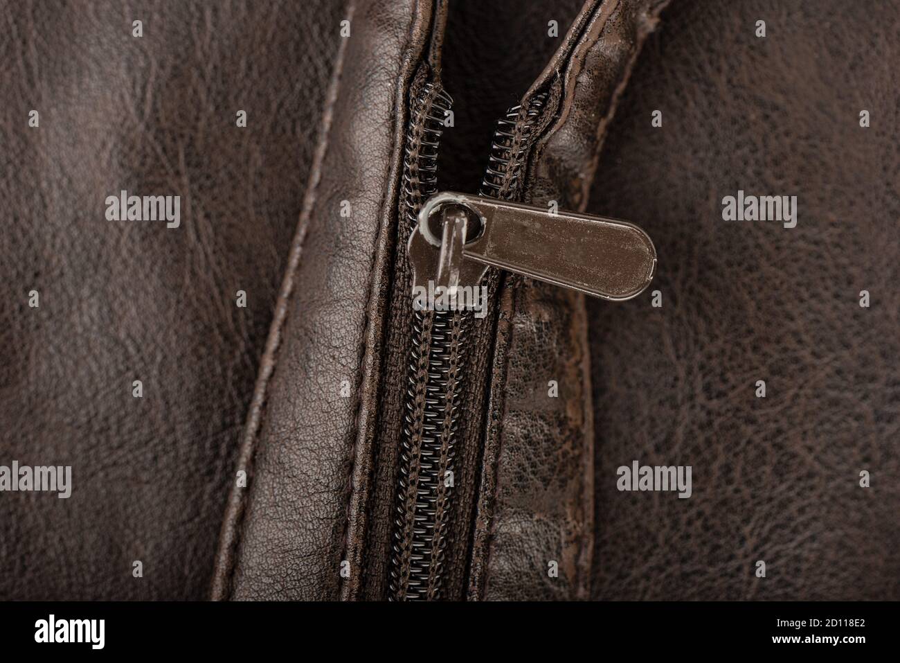 Close-up shot of a zip fastener on a brown belt. The zipper is not fully closed. Stock Photo