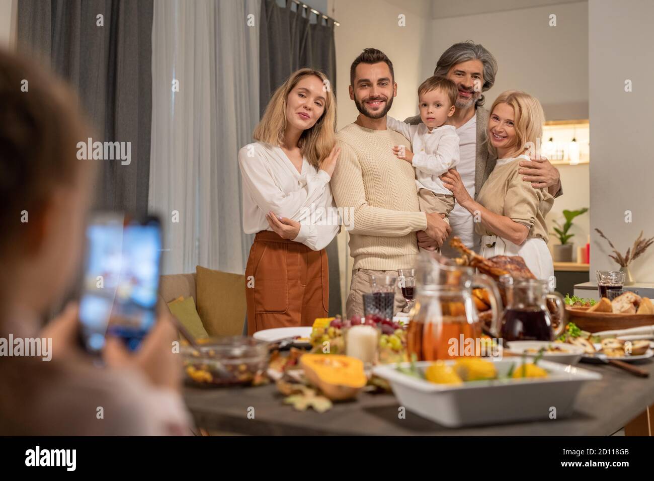 Contemporary affectionate three generation family posing by festive table Stock Photo