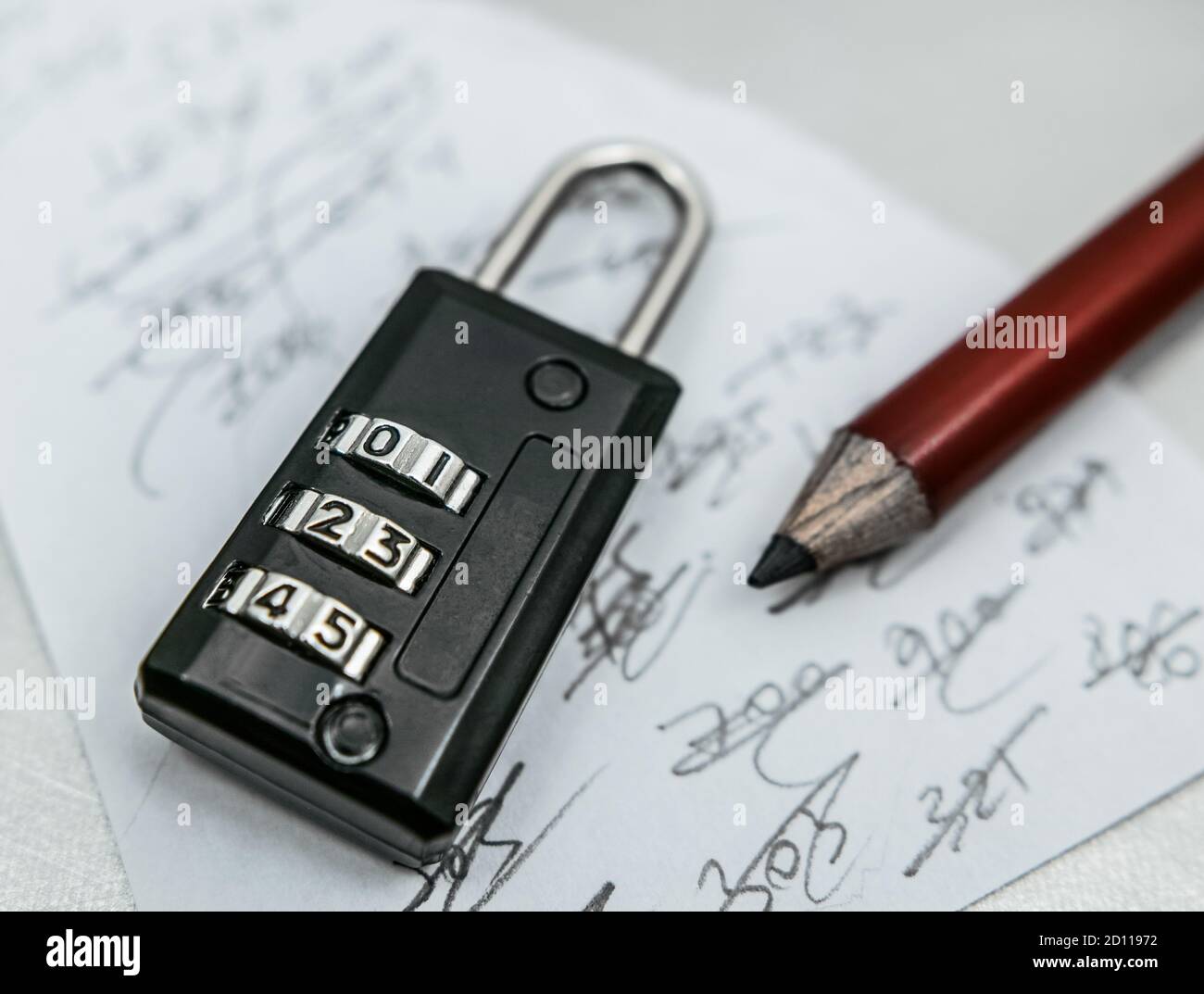 On a piece of paper three-digit codes are written and then crossed out with the pencil. A three-digit code padlock. Stock Photo