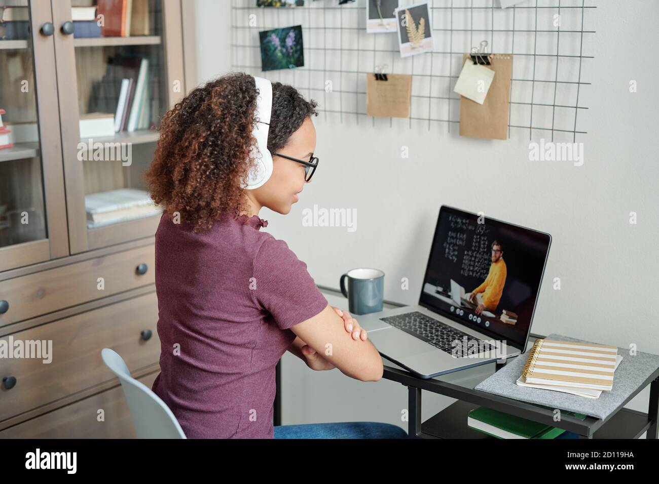 Young mixed-race diligent student having online lesson in home environment Stock Photo