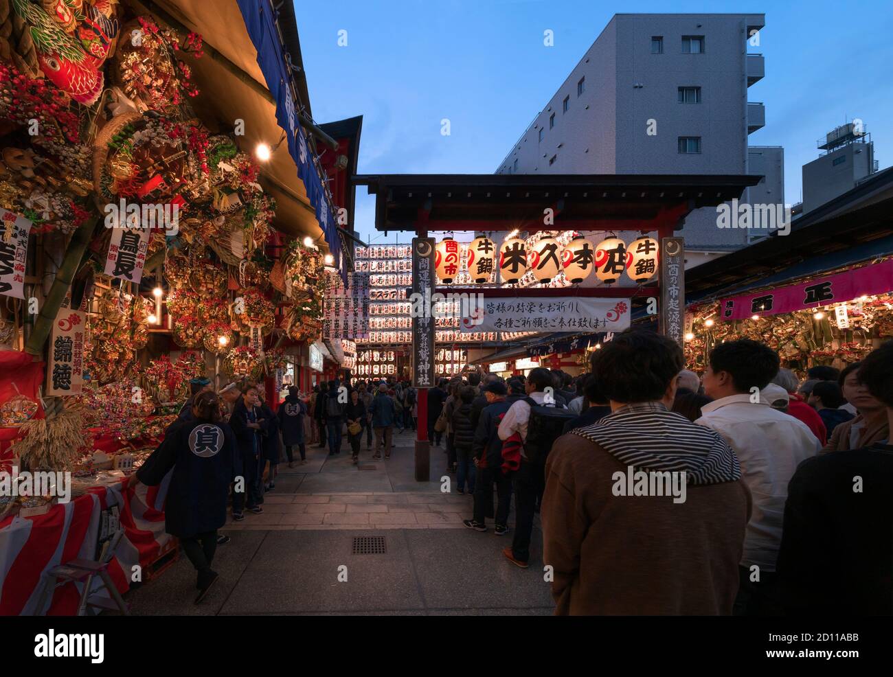 asakusa, japan - november 08 2019: People line up to enter the Ootori shrine decorated at night with luminous paper lanterns to buy auspicious rakes a Stock Photo