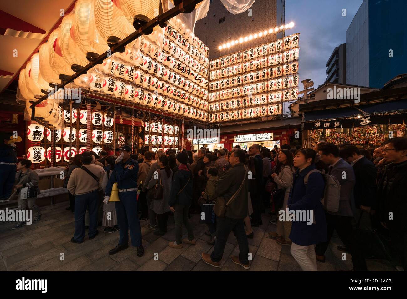 asakusa, japan - november 08 2019: People line up to enter the Ootori shrine decorated at night with luminous paper lanterns to buy auspicious rakes a Stock Photo