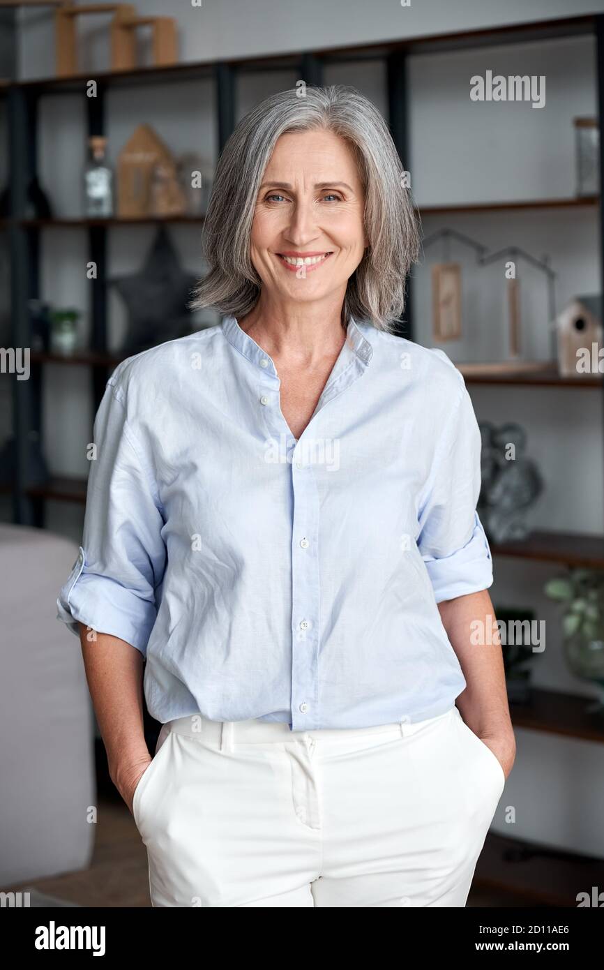 Smiling elegant confident middle aged woman standing in office, portrait. Stock Photo