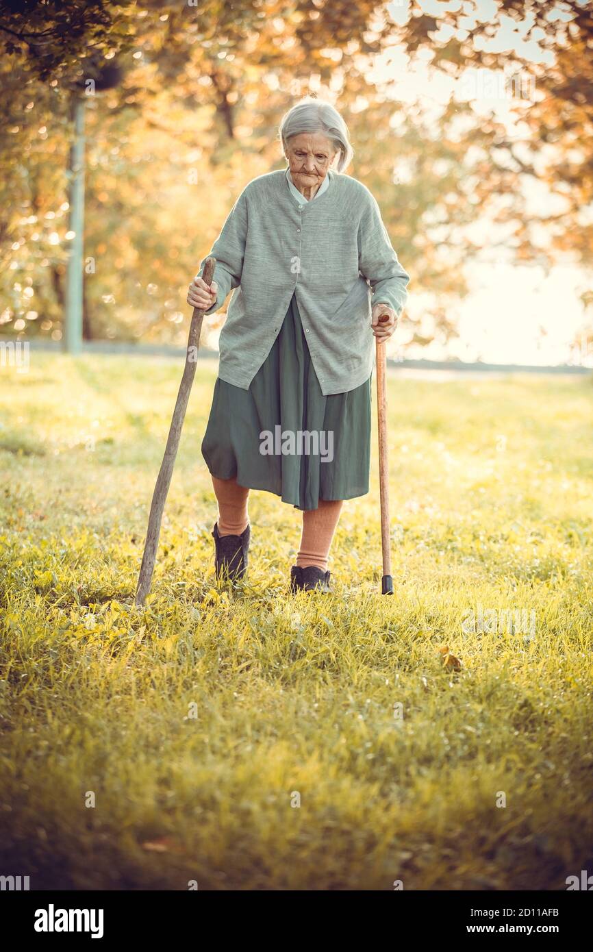 Old woman walking stick park hi-res stock photography and images - Alamy