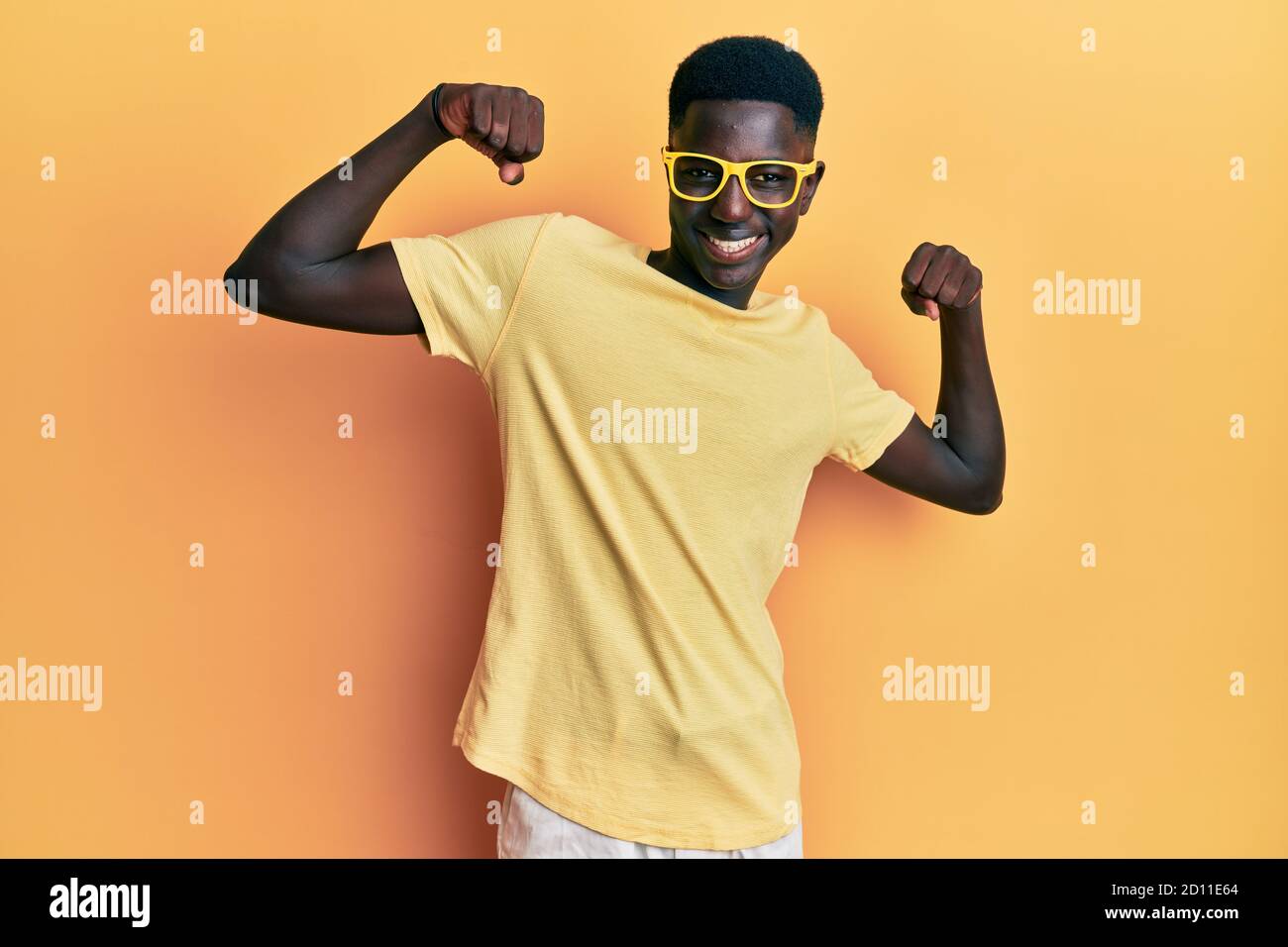 Young african american man wearing casual clothes and glasses showing arms  muscles smiling proud. fitness concept Stock Photo - Alamy