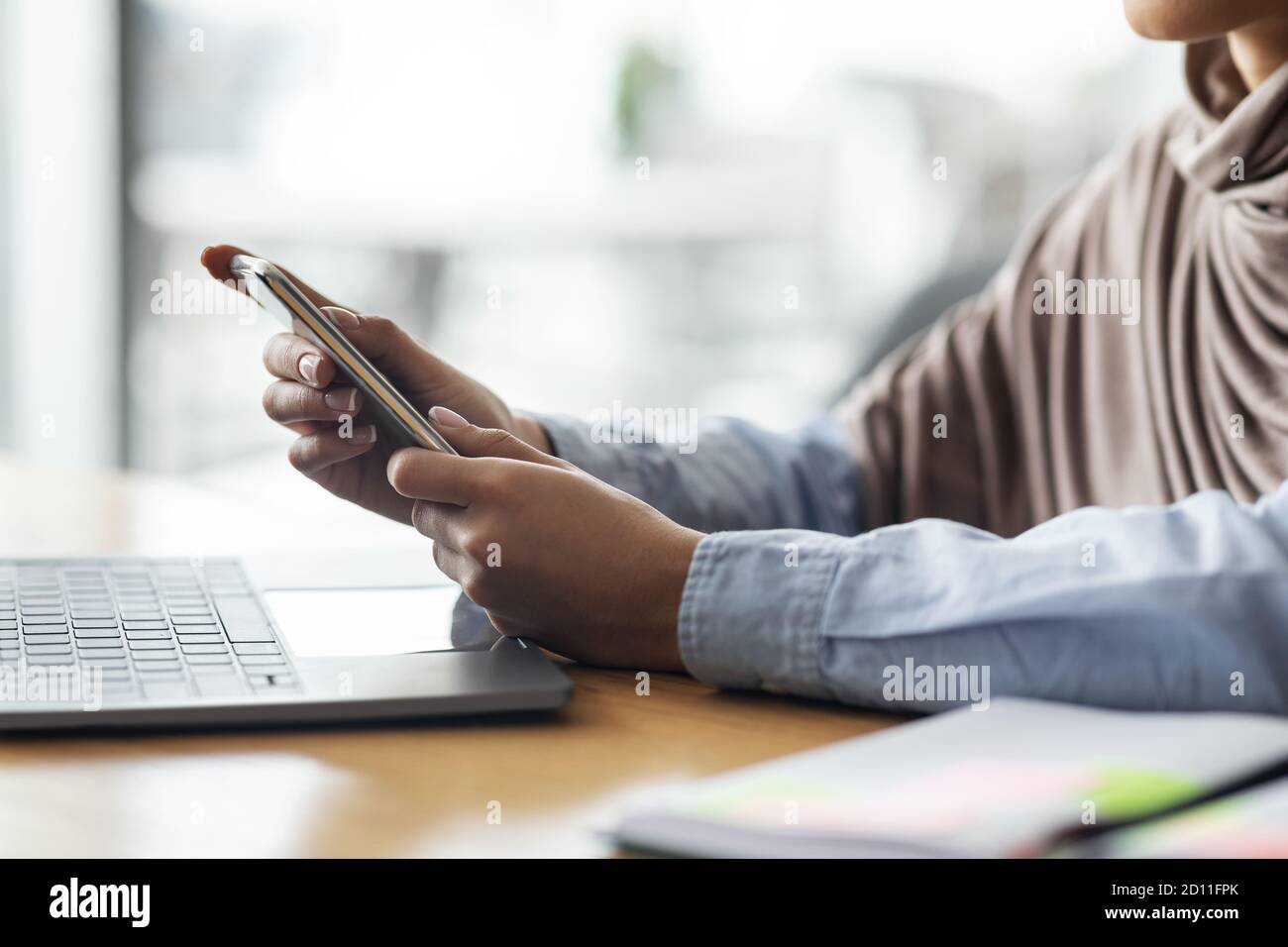 Female hands holding smartphone and using laptop Stock Photo