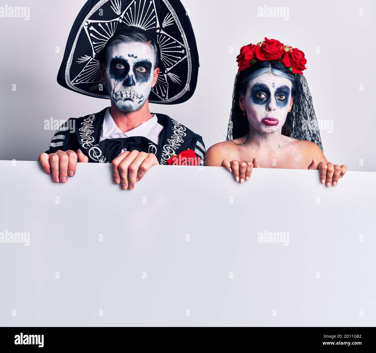 Young couple wearing mexican day of the dead costume holding blank ...