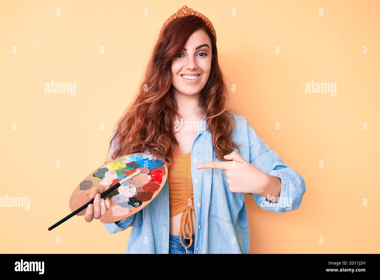 Young beautiful woman holding paintbrush and palette smiling happy ...