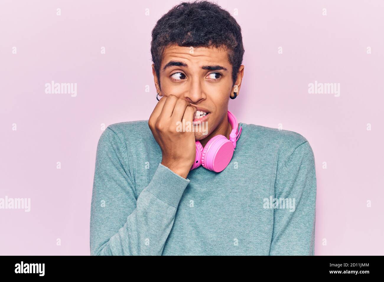 Young african amercian man listening to music using headphones looking