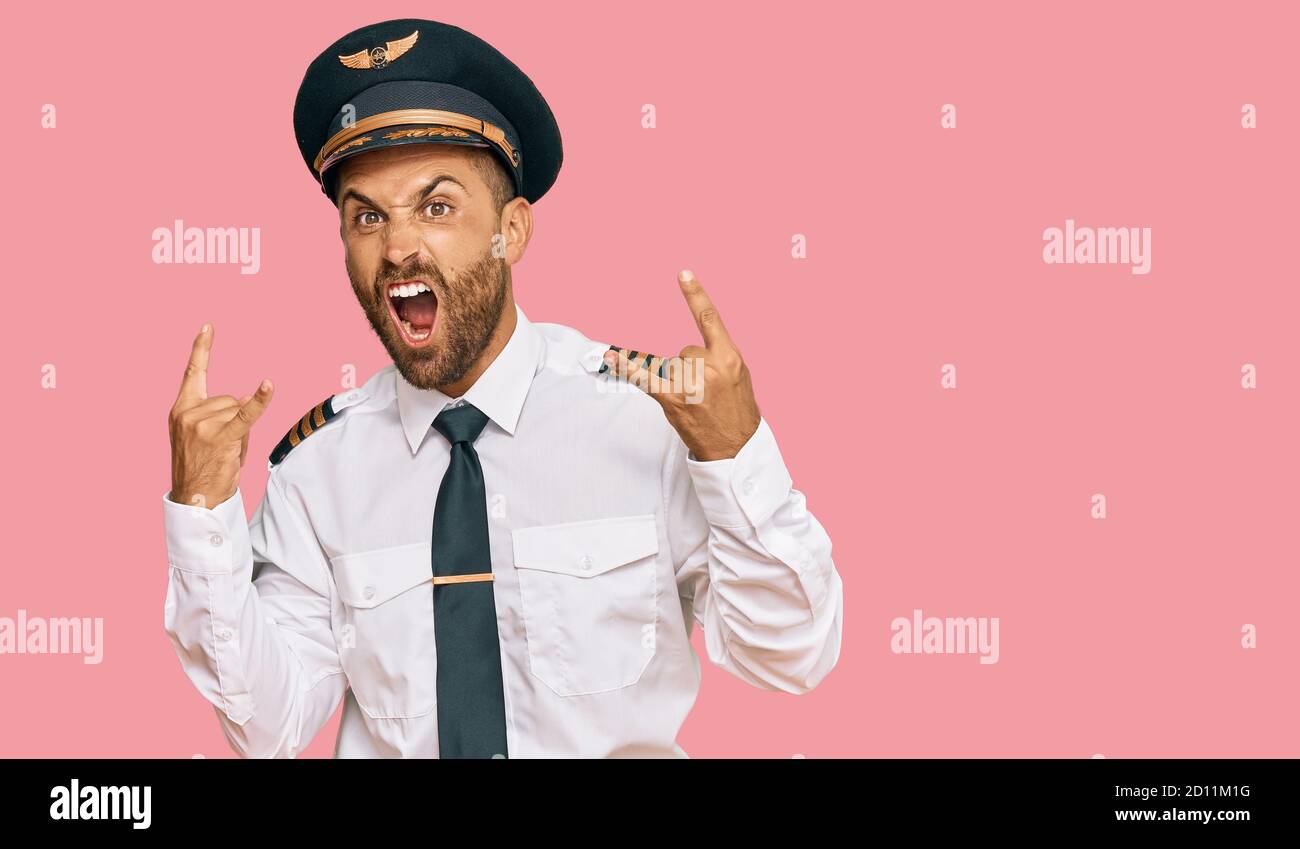 Handsome man with beard wearing airplane pilot uniform shouting with ...
