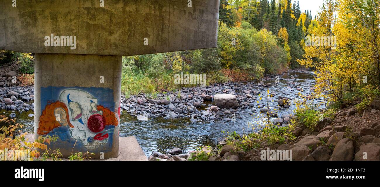 Panorama scene of a sad clown face painted on a bridge support along the Cascade River in Cook County, North Shore of Lake Superior, Minnesota Stock Photo