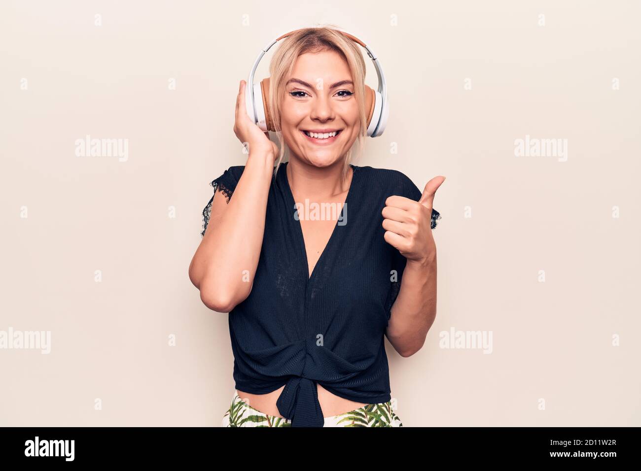 Young beautiful blonde woman listening to music using headphones over ...