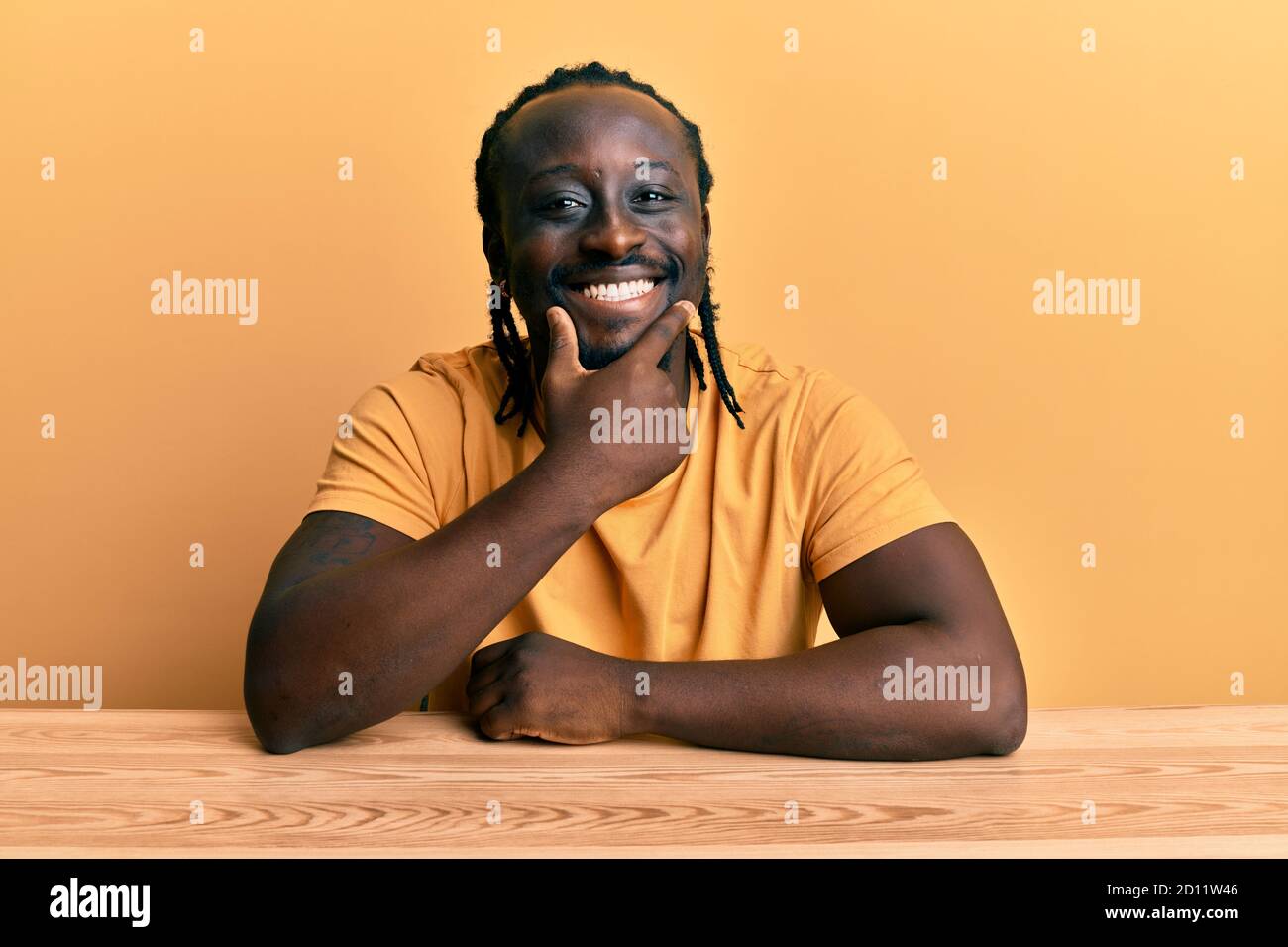 Handsome young black man wearing casual clothes sitting on the table ...