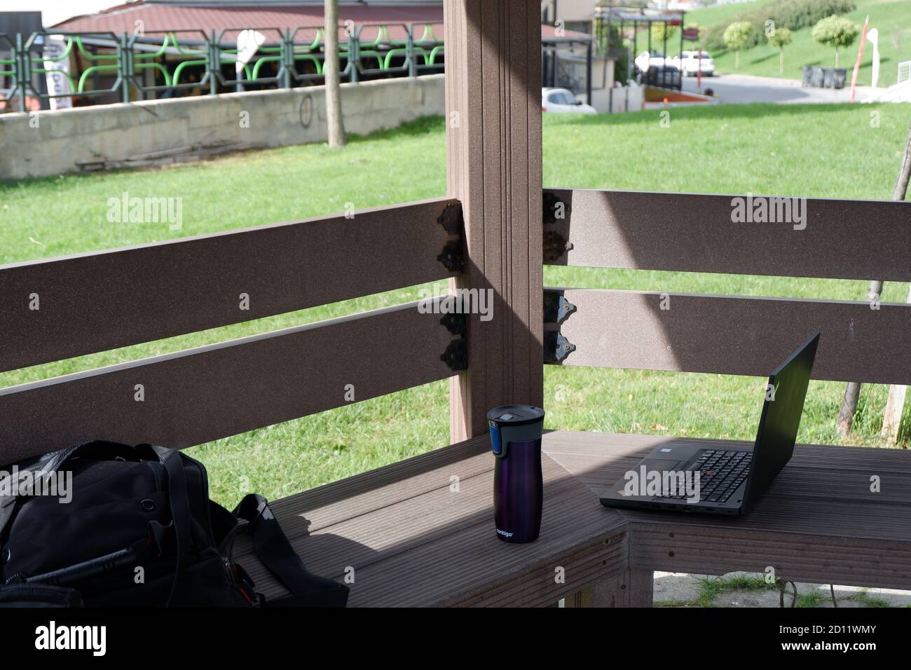 Working outdoor out of office at the days of quarantine. Laptop, bag and coffee at outdoor. Stock Photo