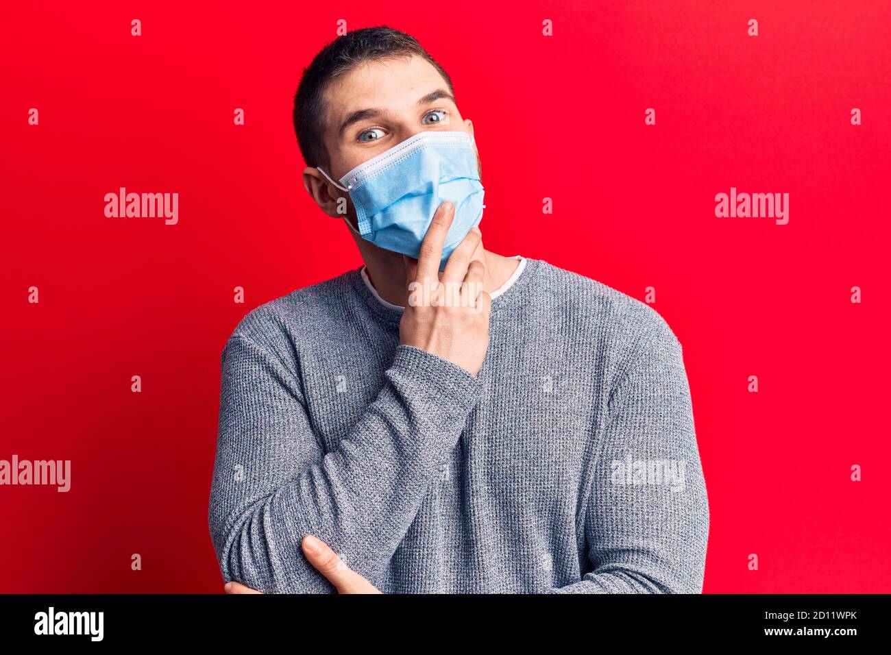 Young handsome man wearing medical mask smiling looking confident at ...