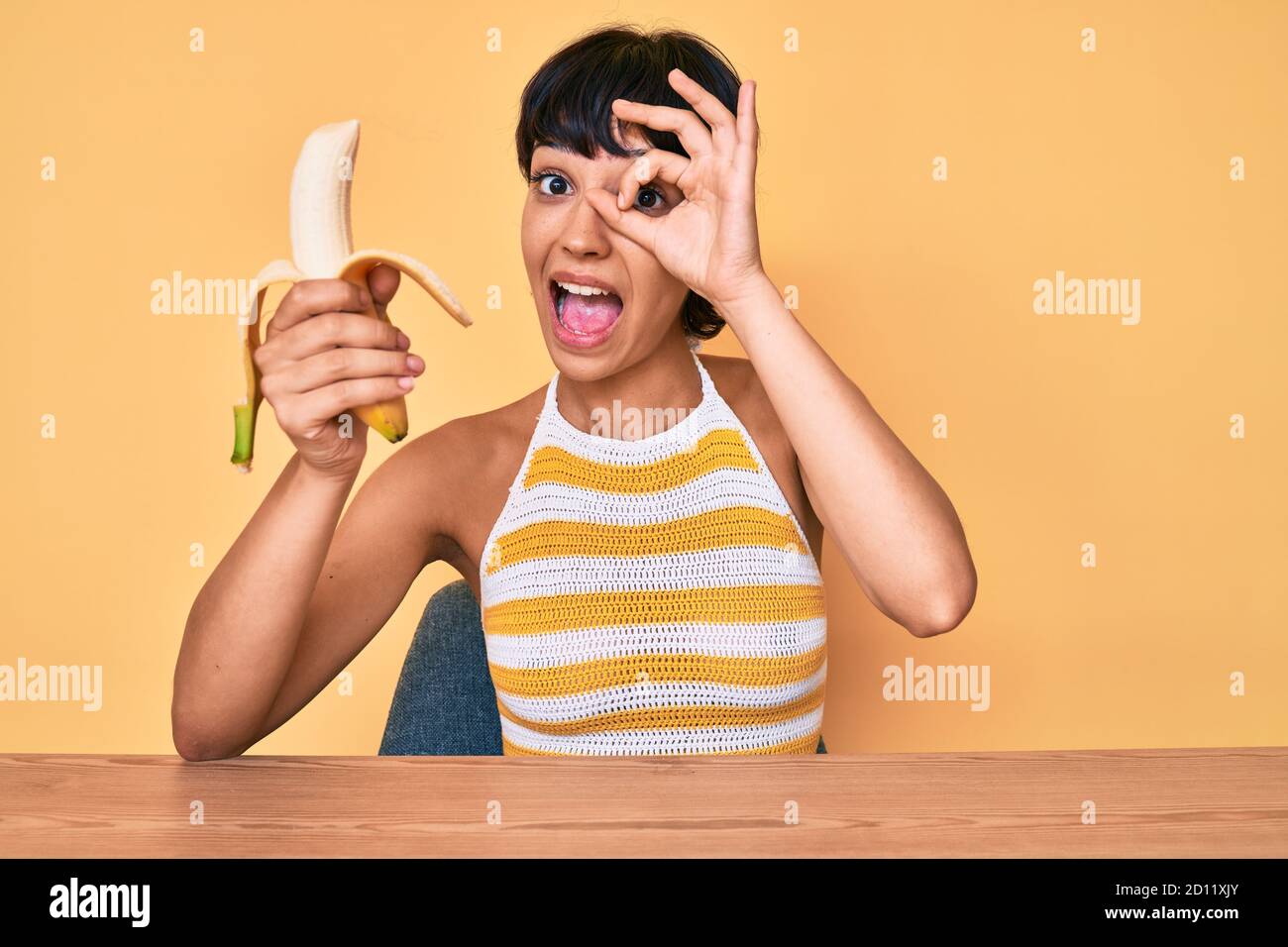 Brunette teenager girl eating banana as healthy snack smiling happy