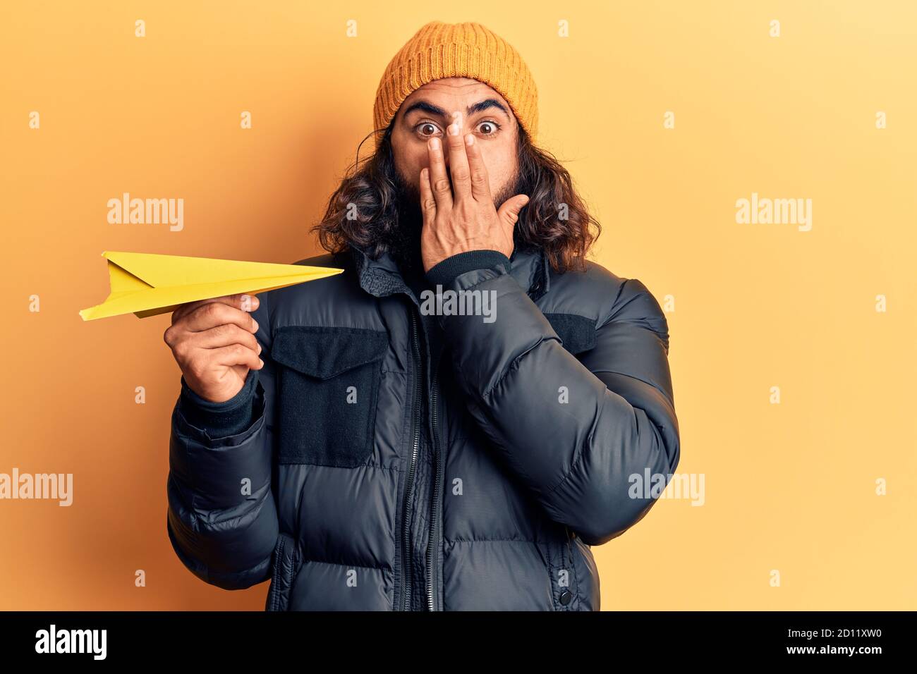 Afraid Paper Young arab man holding paper airplane covering mouth with hand, shocked ...