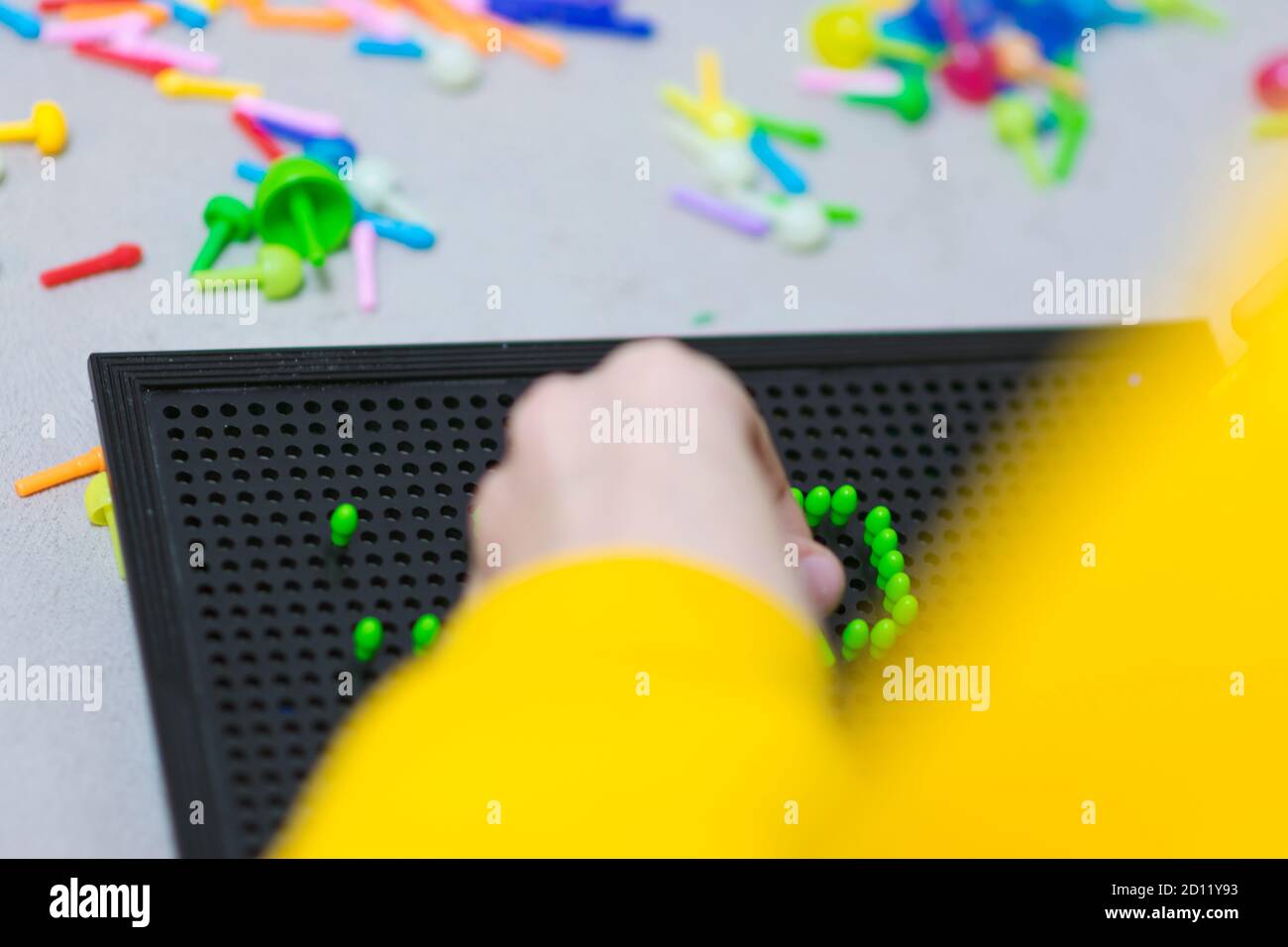 Child playing creative pin board game with colorful plasitc peaces