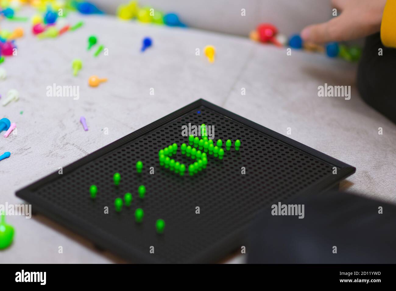 Child playing creative pin board game with colorful plasitc peaces