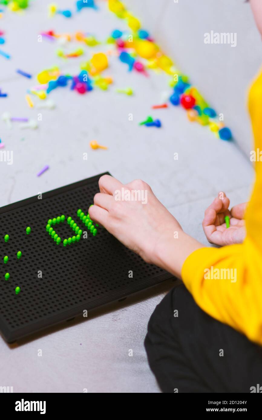 Child playing creative pin board game with colorful plasitc peaces