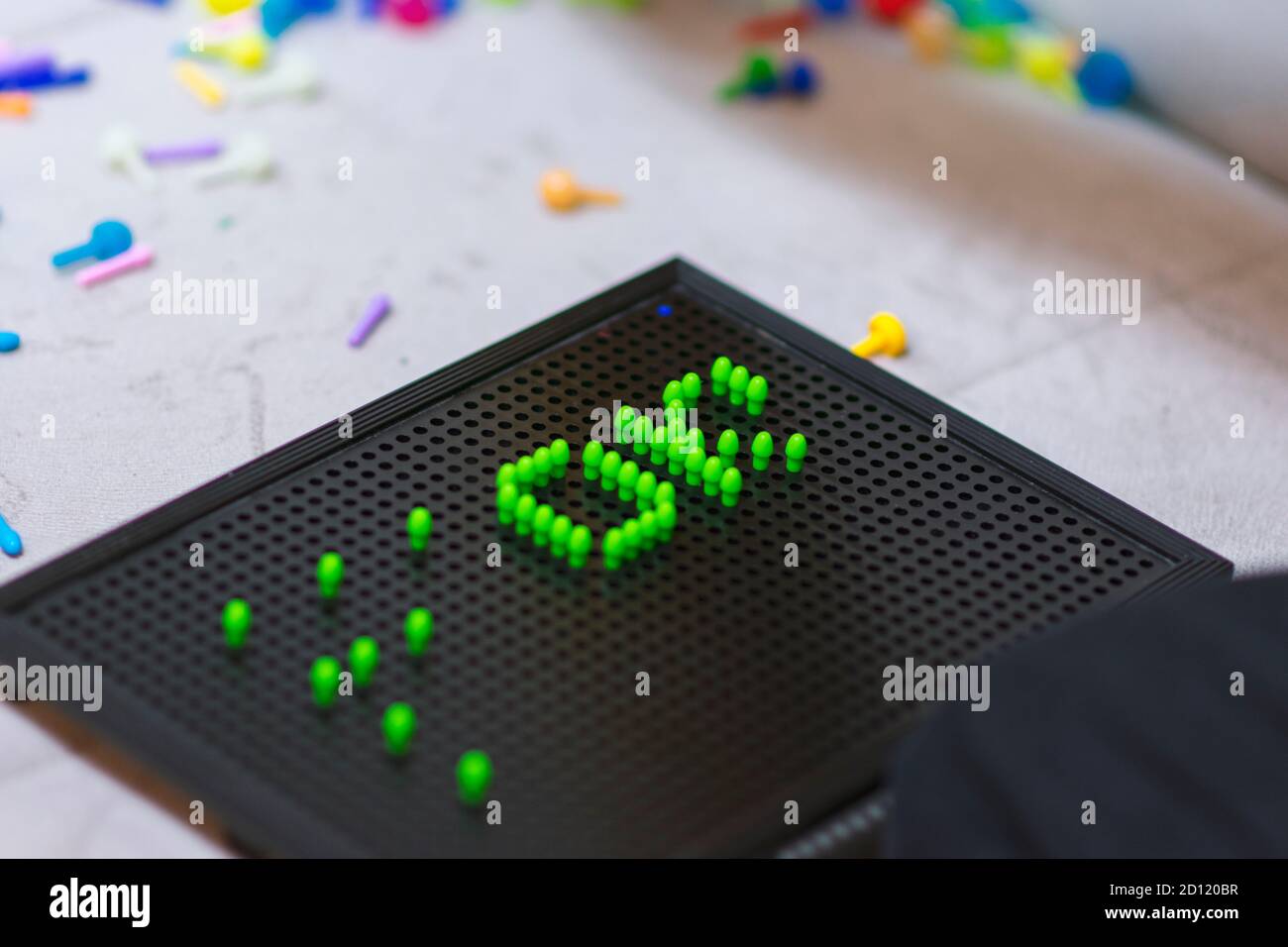 Child playing creative pin board game with colorful plasitc peaces