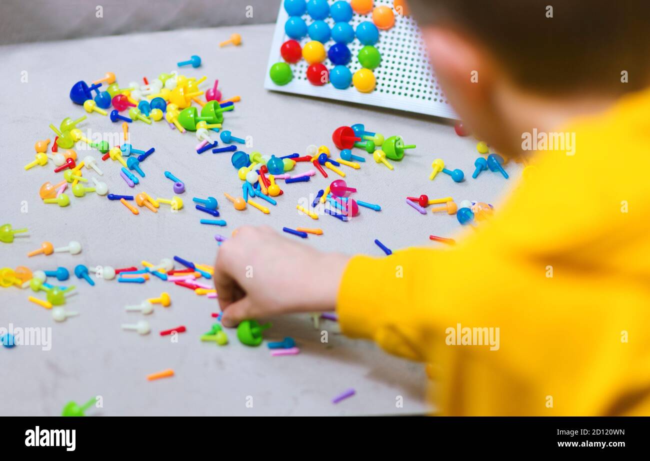Child playing creative pin board game with colorful plasitc peaces