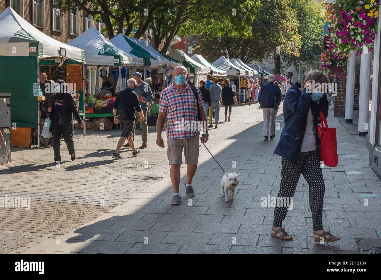 Man wearing face mask walks with his dog through Canterbury High Street on a sunny day. Stock Photo
