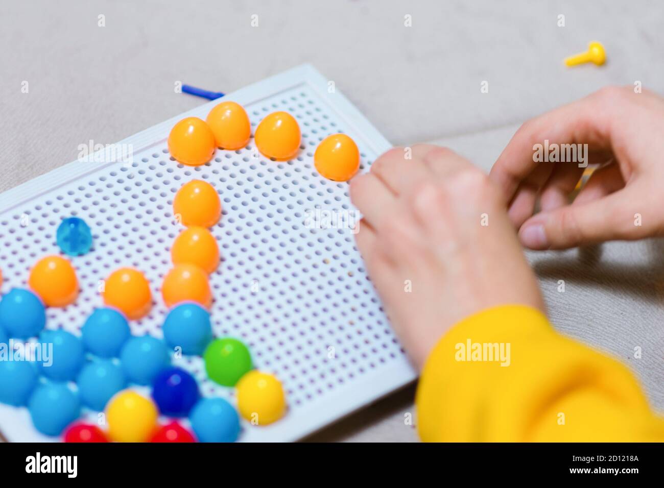 Child playing creative pin board game with colorful plasitc peaces