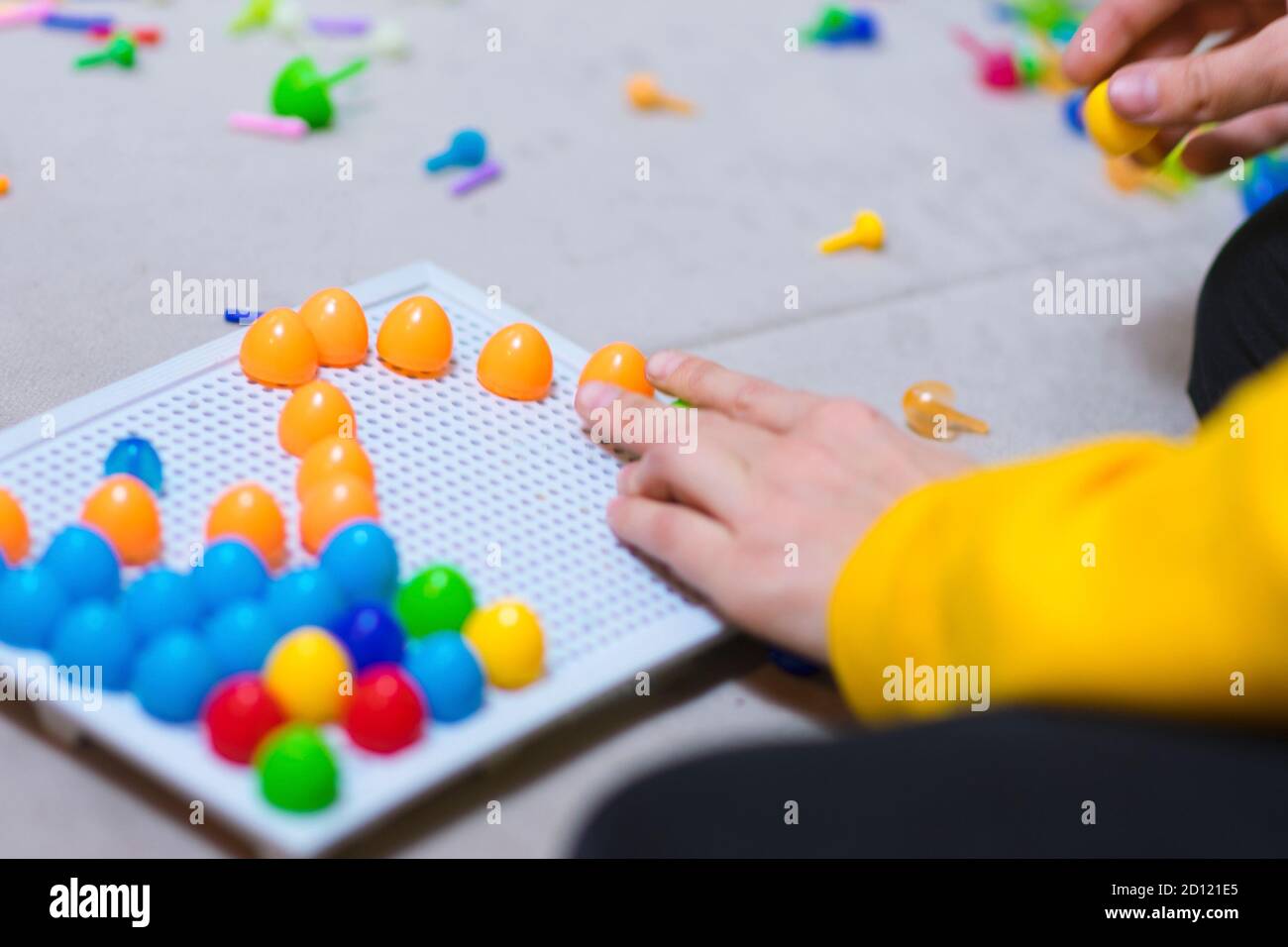 Child playing creative pin board game with colorful plasitc peaces
