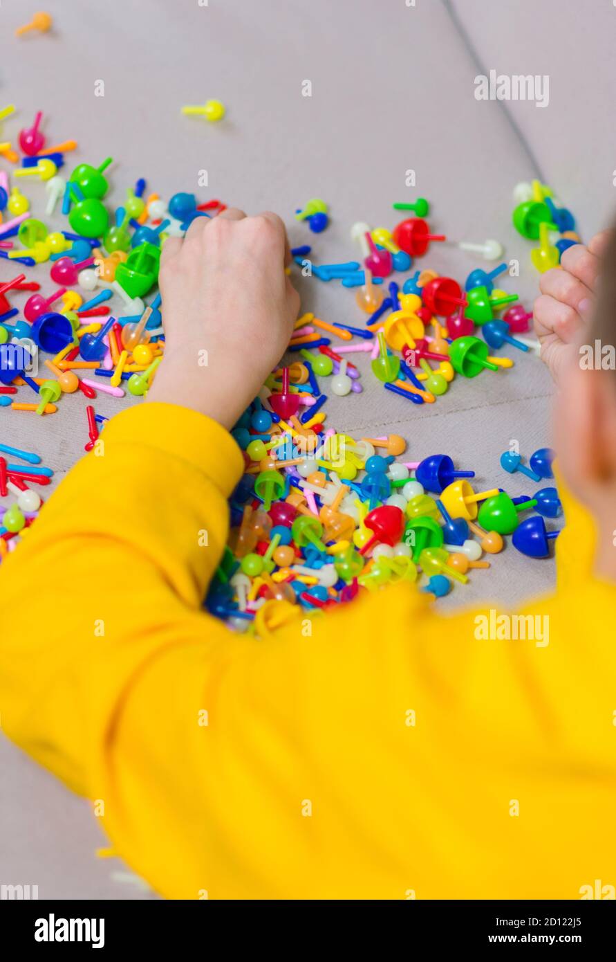 Child playing creative pin board game with colorful plasitc peaces