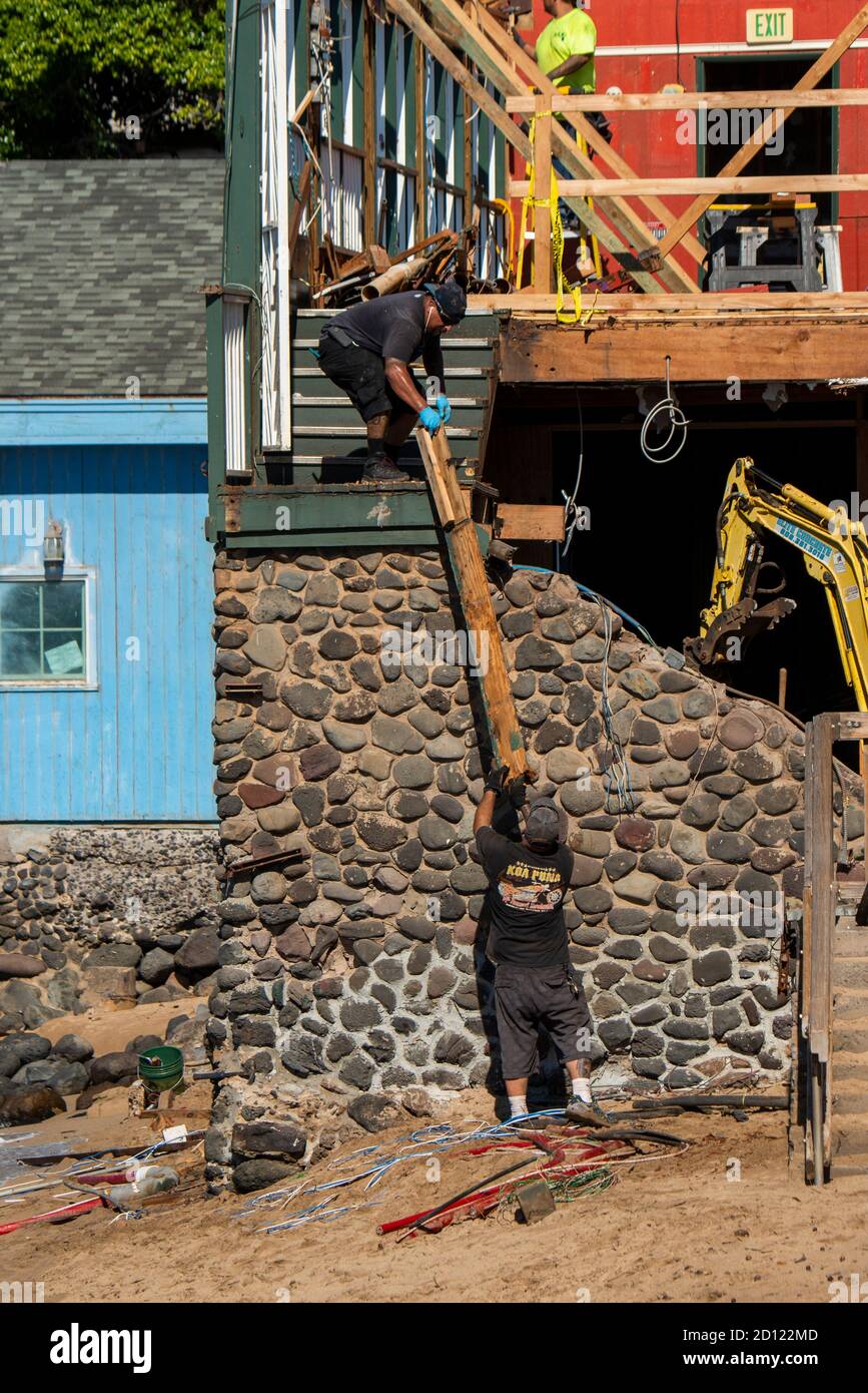 Maui, Hawaii. Construction worker handing material to another worker in a building remodel in Lahaina. Stock Photo