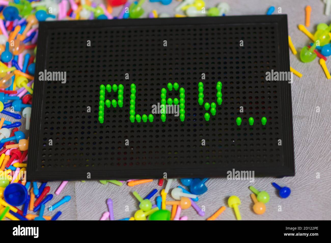 Child playing creative pin board game with colorful plasitc peaces