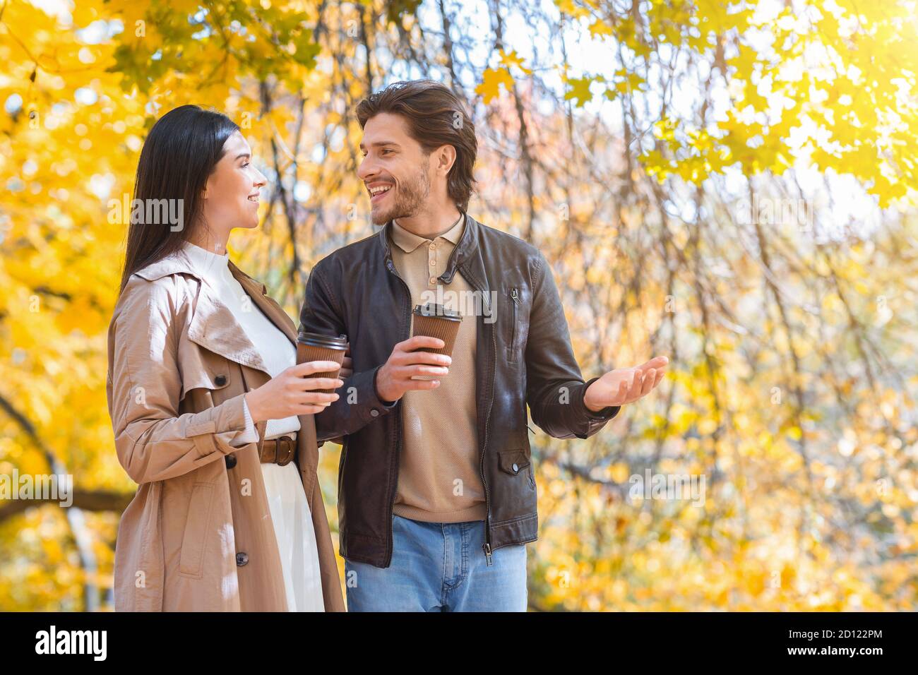 Happily married couple with cups of coffee walking by forest Stock Photo