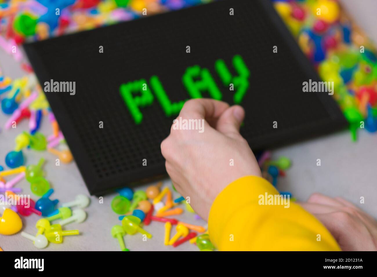 Child playing creative pin board game with colorful plasitc peaces