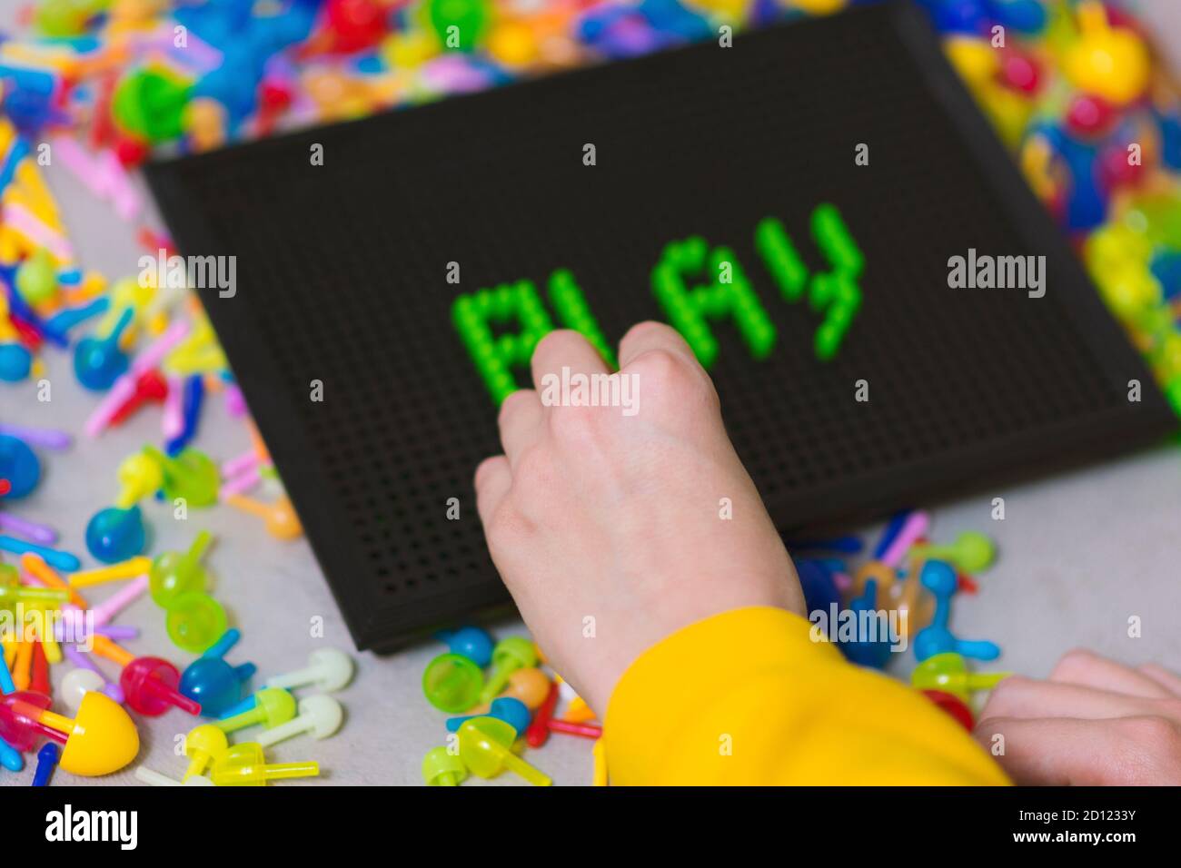 Child playing creative pin board game with colorful plasitc peaces