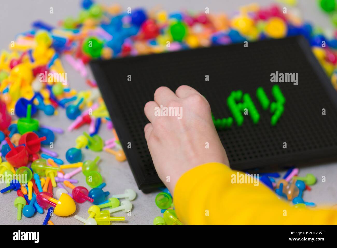 Child playing creative pin board game with colorful plasitc peaces