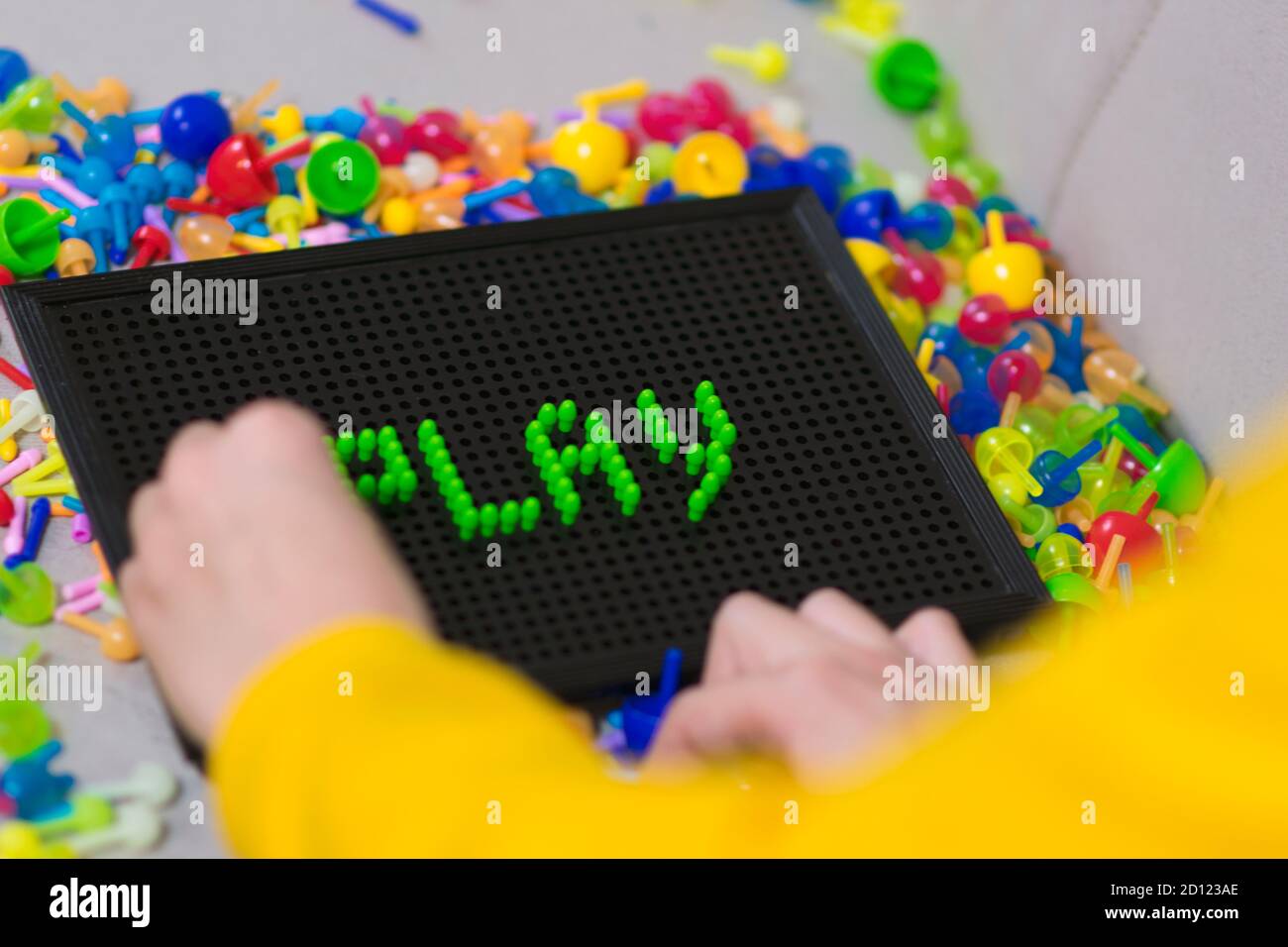 Child playing creative pin board game with colorful plasitc peaces