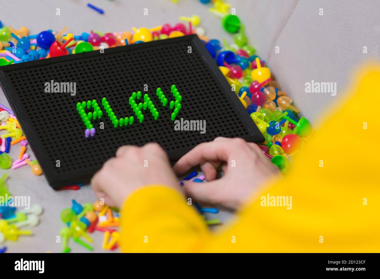 Child playing creative pin board game with colorful plasitc peaces