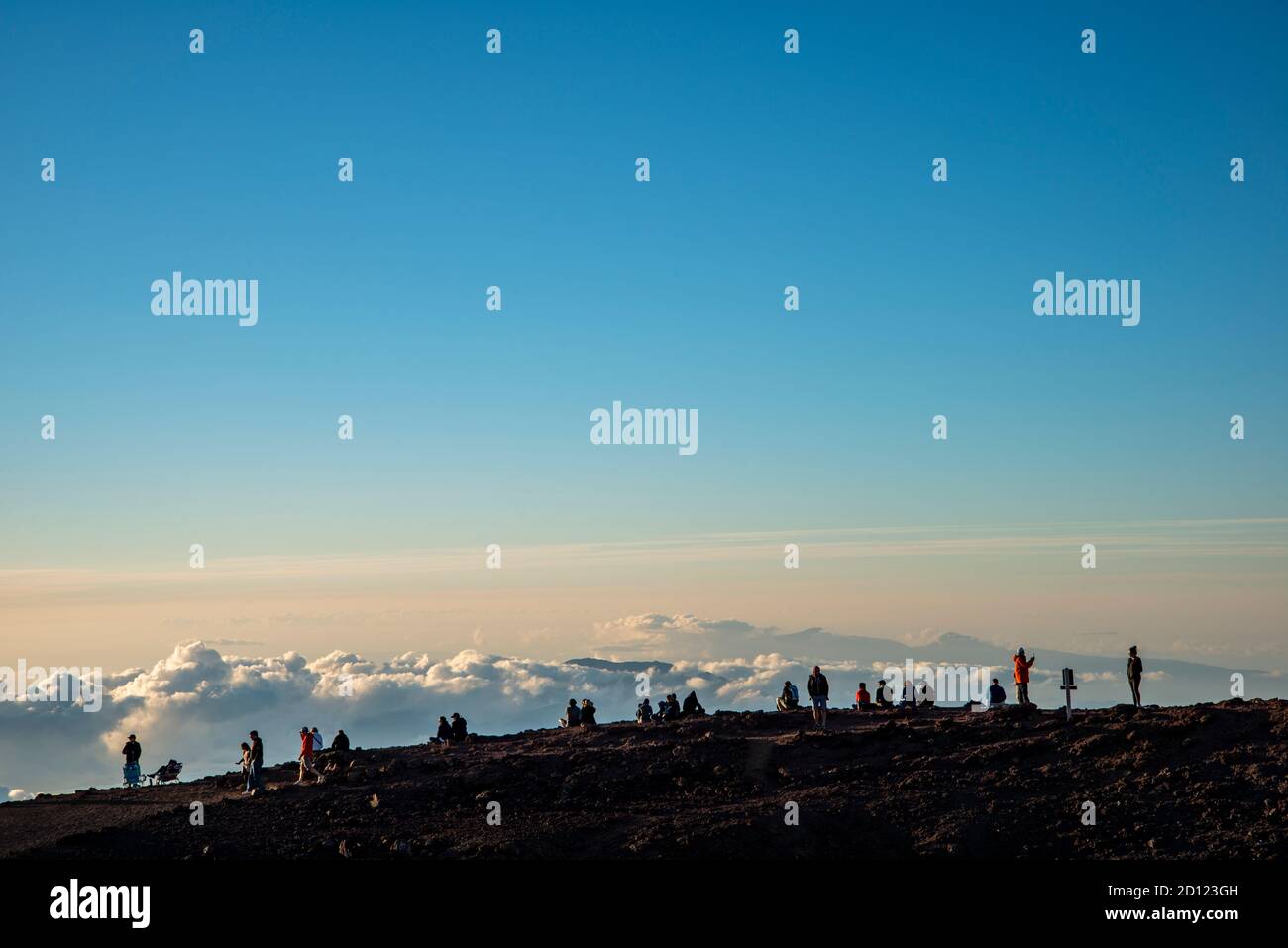 Maui, Hawaii.  Visitors on the Haleakala Crater in the Haleakala National Park watch the sunset while above the clouds. Stock Photo
