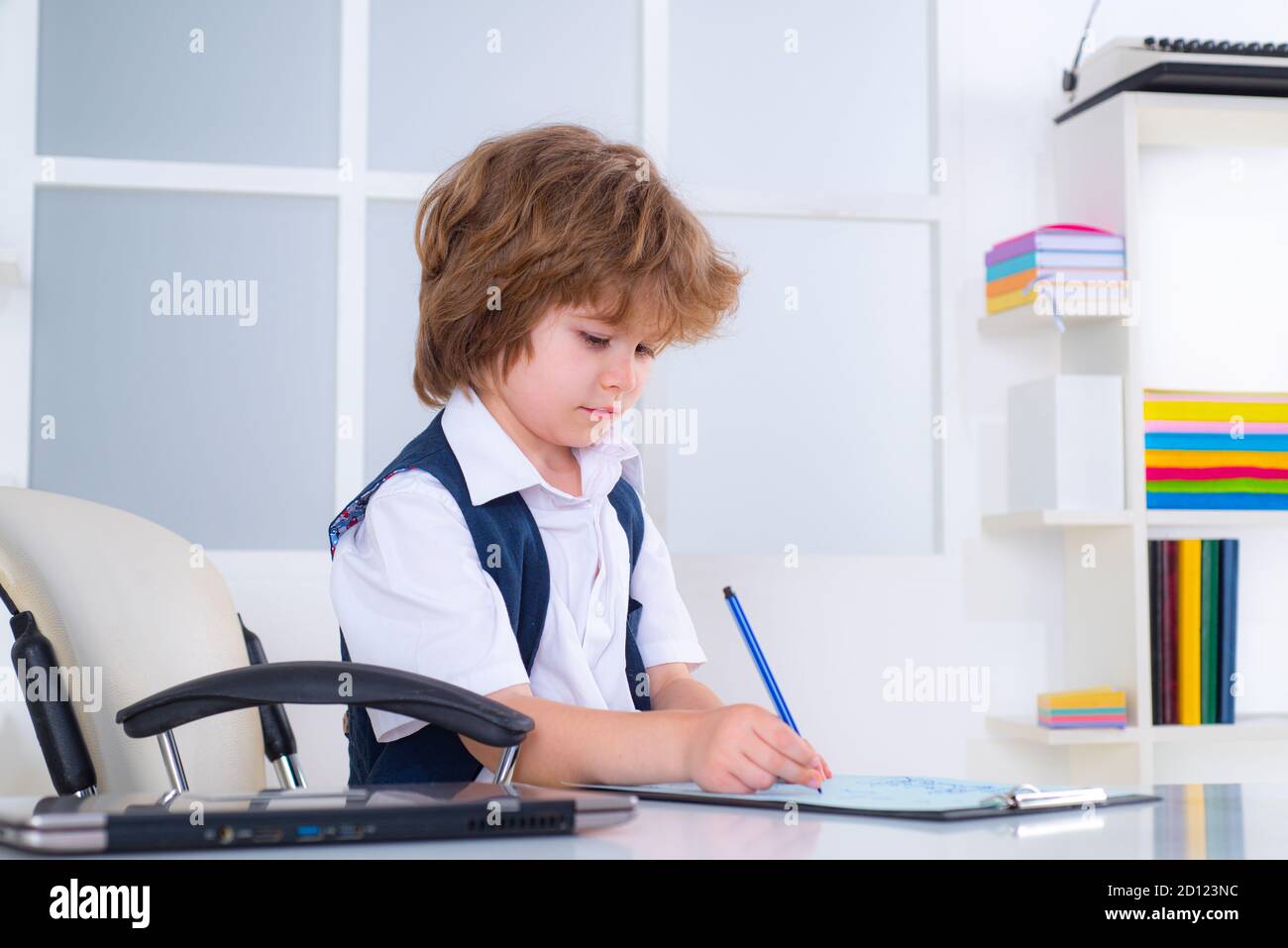 Portrait of little kid boy man sitting at his desk in the office. Child