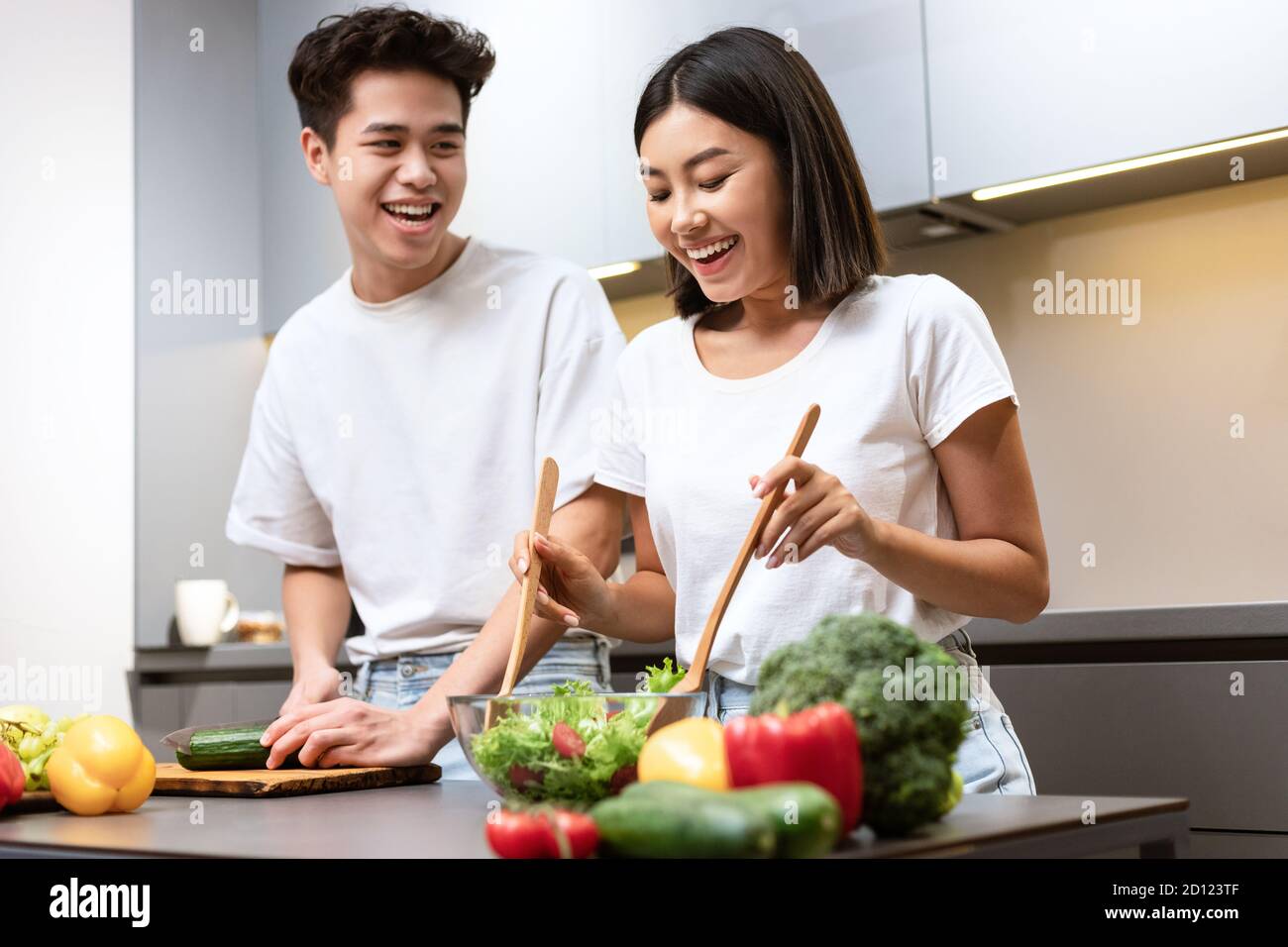 Happy Korean Couple Cooking And Laughing Preparing Dinner At Home Stock Photo