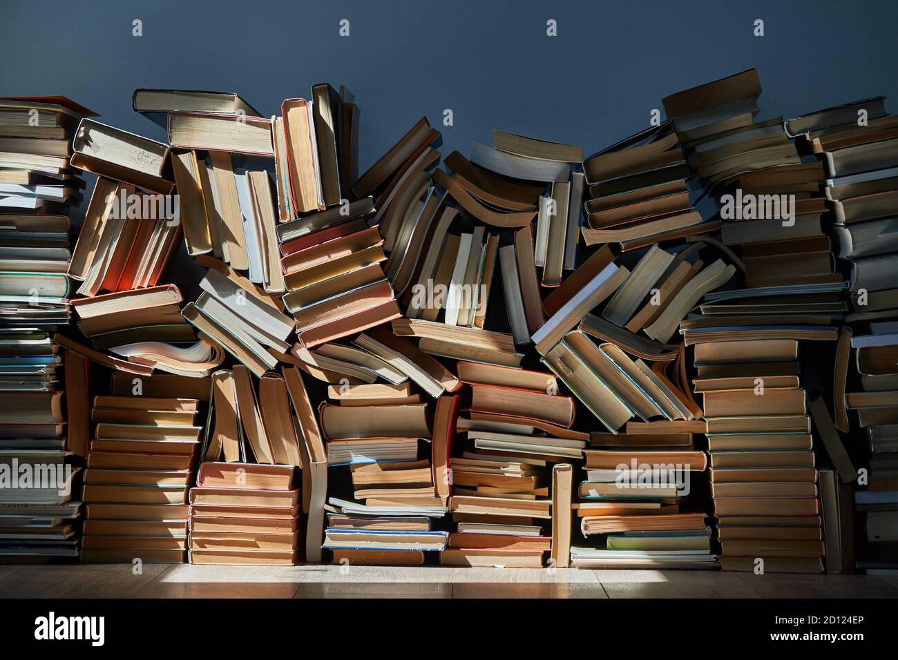 Wall of books piled up in the attic Stock Photo