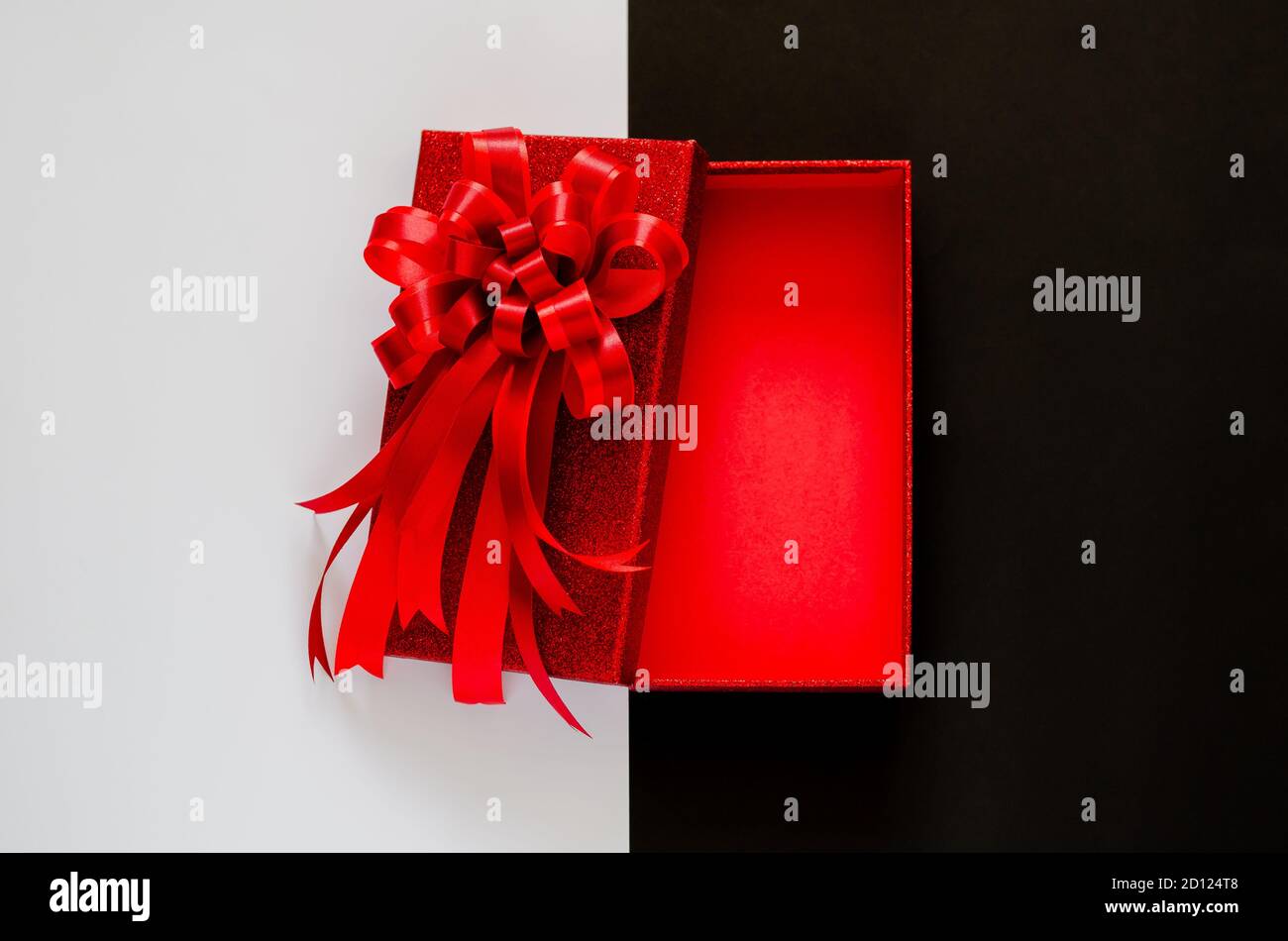 Red christmas box with red bow ribbon on black and white background