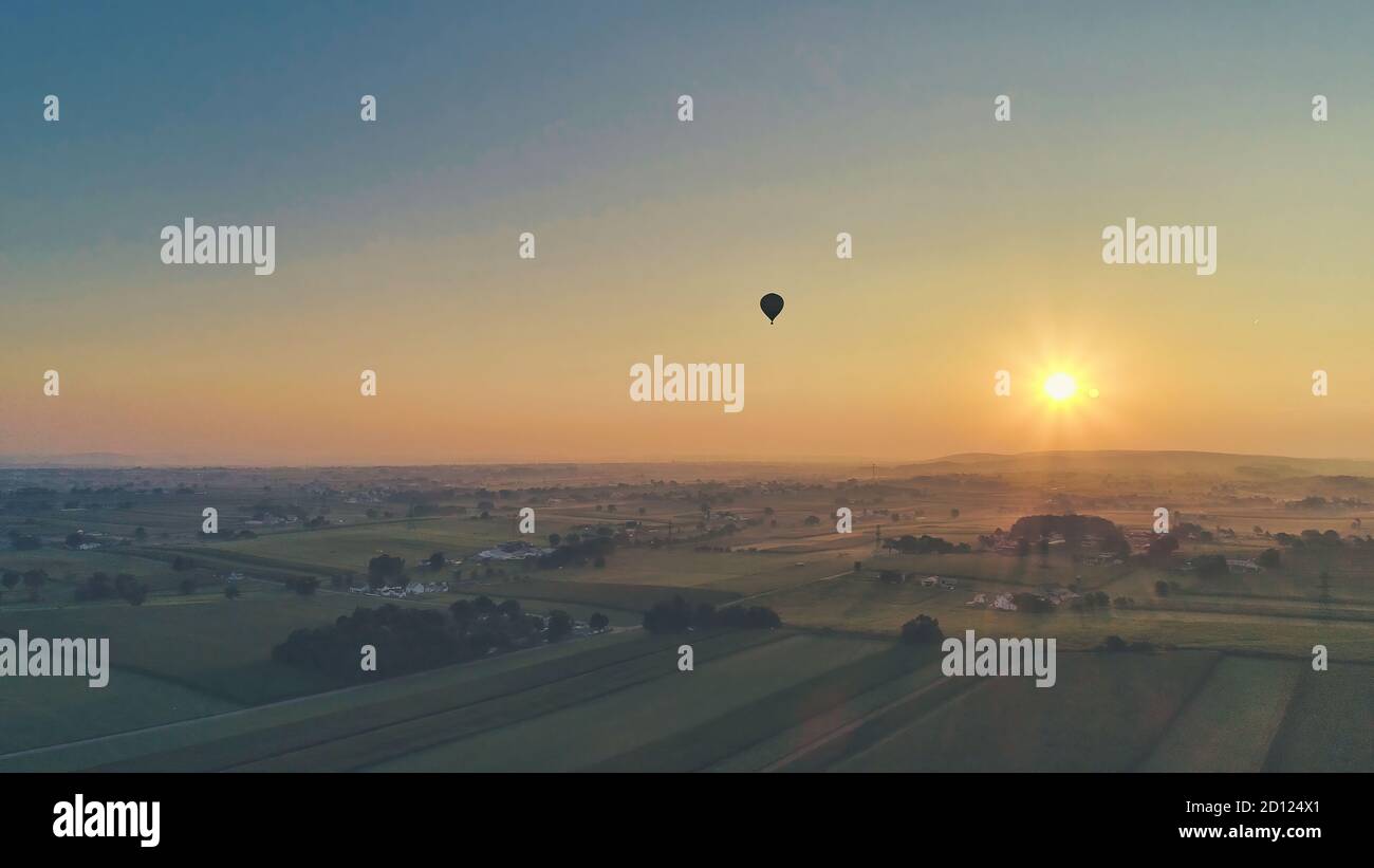 Aerial view of a summer sunset over farm lands with blue skies and red ...