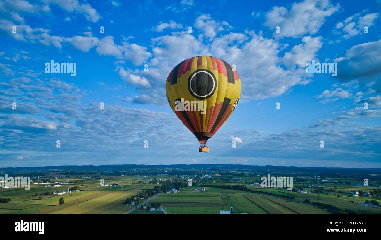 Aerial view of blue sky and multiple clouds and a hot air balloon floating thru it Stock Photo